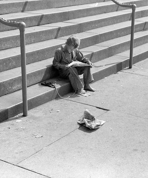 Boy reading funny paper on steps of public library, Milwaukee, Wisconsin  Photo: Russell Lee