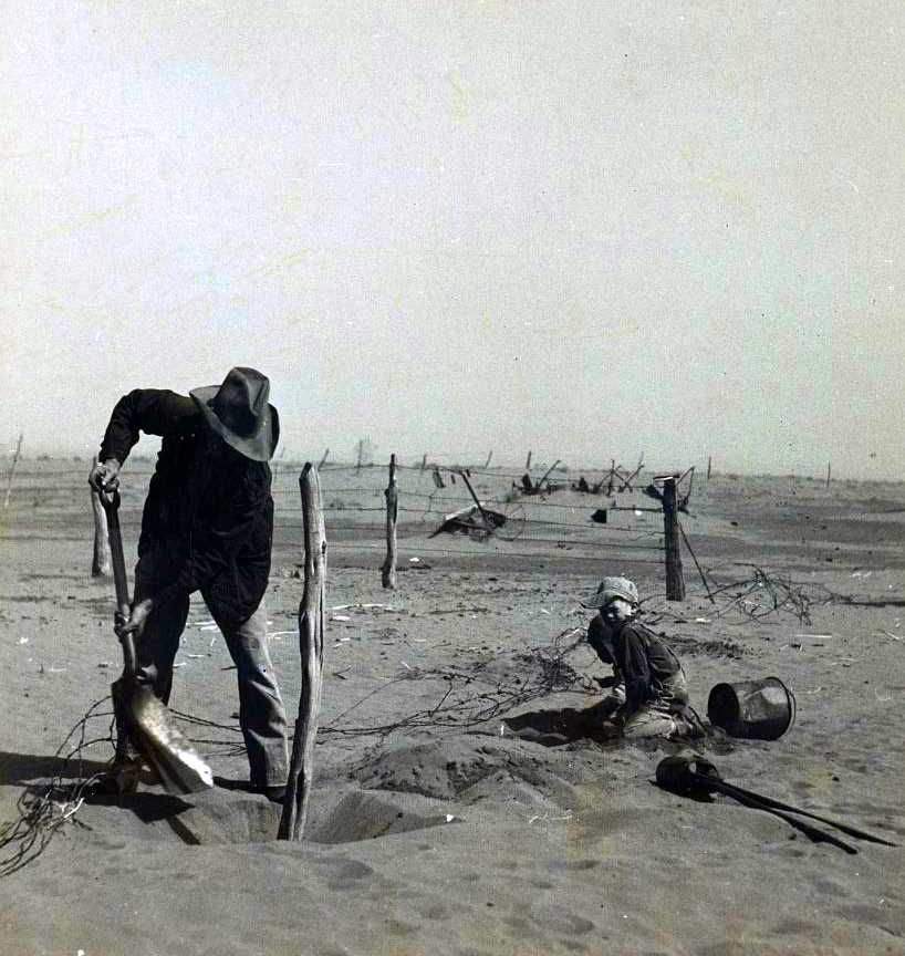 Dust bowl farmer raising fence to keep it from being buried under drifting sand. Cimarron County, Oklahoma Photo: Arthur Rothstein