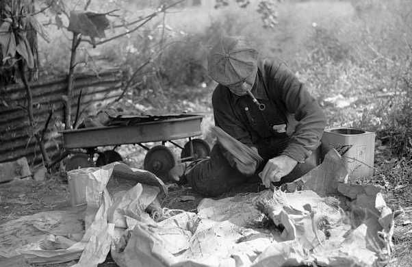 Man in hobo jungle killing turtle to make soup, Minneapolis, Minnesota]